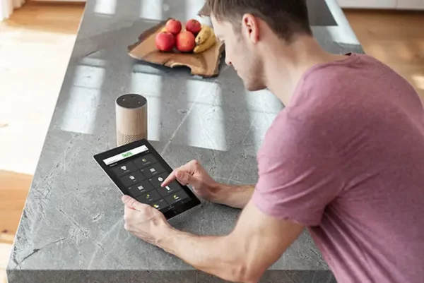 Homme sur sa tablette qui contrôle à distance sa Chaudière à condensation granulés Pellematic Smart XS